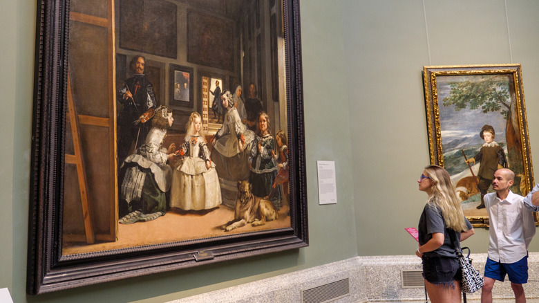 two people staring at las meninas painting inside museum