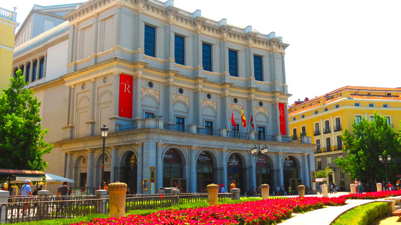exterior of the Royal Theater of Madrid lined with red flowers