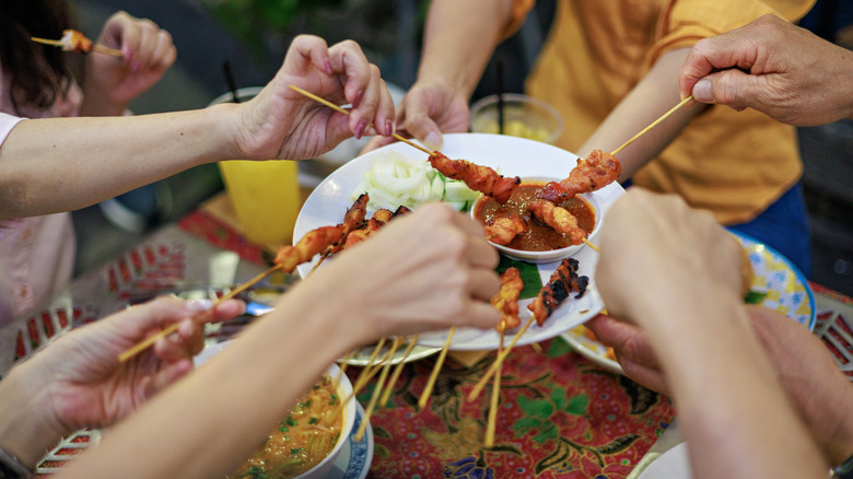Travelers reaching for food skewers in the historical city of George Town