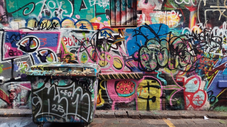 Colorful, layered graffiti covers the walls and a dumpster on Hosier Lane in Melbourne