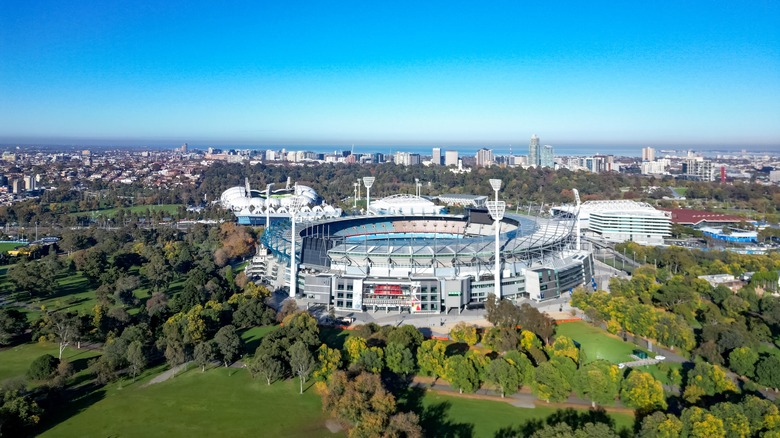Aerial view of Melbourne city skyline with the iconic Melbourne Cricket Ground (MCG) in the foreground on a clear sunny day in Victoria, Australia.