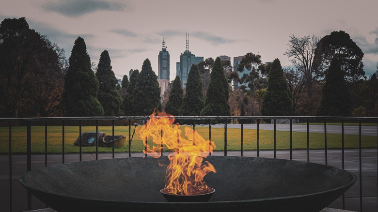 The eternal fire burning at the Shrine of Remembrance, Melbourne with the skyline in the background on a cloudy day