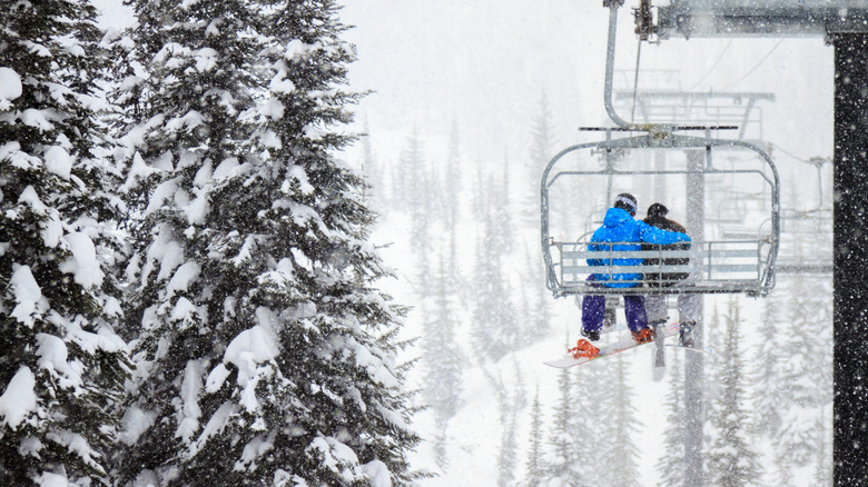 Skiing couple on a chairlift while snow falls
