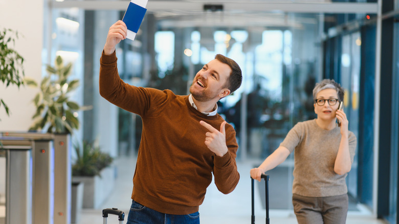 A man posing with his passport at the airport