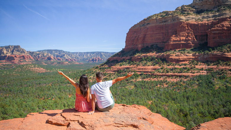 Couple putting their arms out on top of an rocky desert overlook near Sedona, Arizona