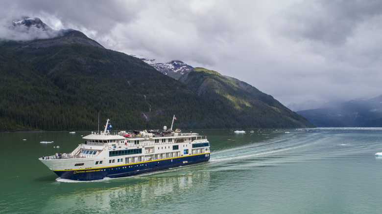 A Lindblad National Geographic passenger ship in Tracy Arm Fjord, Alaska, with mountains in the background.