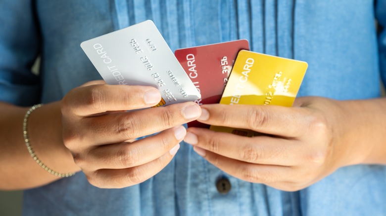 A person holds three banking cards.