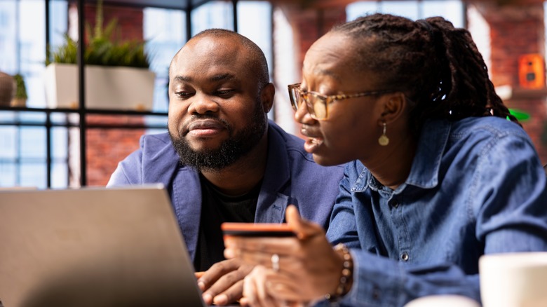 A couple makes online reservations with a laptop and credit card.