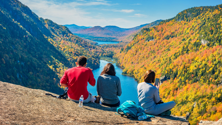 Three resting hikers enjoy the view of the lakes below in the Adirondacks, New York