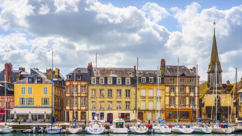 Colorful houses, a church, and sailboats line the Honfleur Harbor, Normandy, France