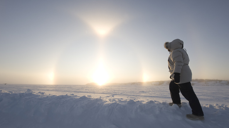 A woman watches the "sundogs" phenomenon, where ice in the air reflects images of the sun
