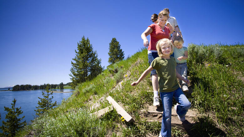 A family with children walk a trail overlooking Yellowstone Lake.