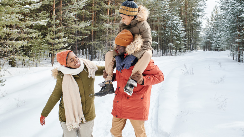 Family walking along a snowy woodside path.