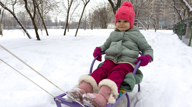 A little girl sledding in the winter.