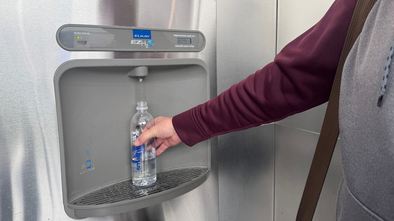 A person refilling a water bottle at a water fountain