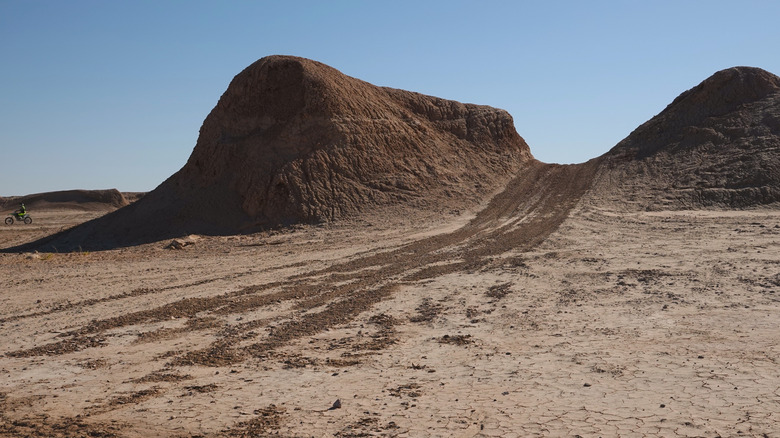 Tire tracks in sand leading up between hills in Ocotillo Wells State Vehicular Recreation Area in Borrego Springs, California