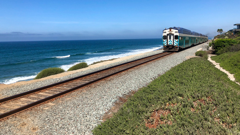 Amtrak Pacific Surfliner train with blue ocean and blue sky, passing by Del Mar, San Diego, California.