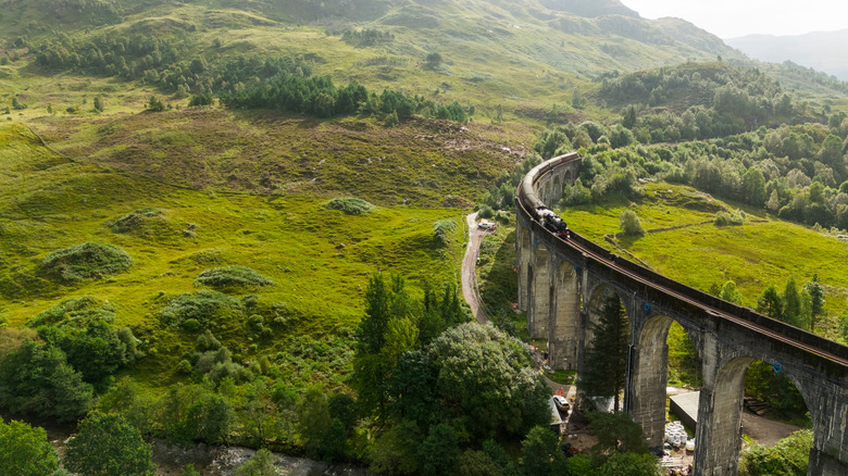 Jacobite Steam Train,snakes through the Scottish Highlands and billows steam as it crosses the Glenfinnan Viaduct.