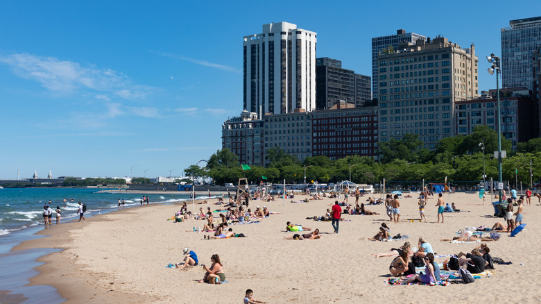 Oak Street Beach in the summer, with people sitting on the sand