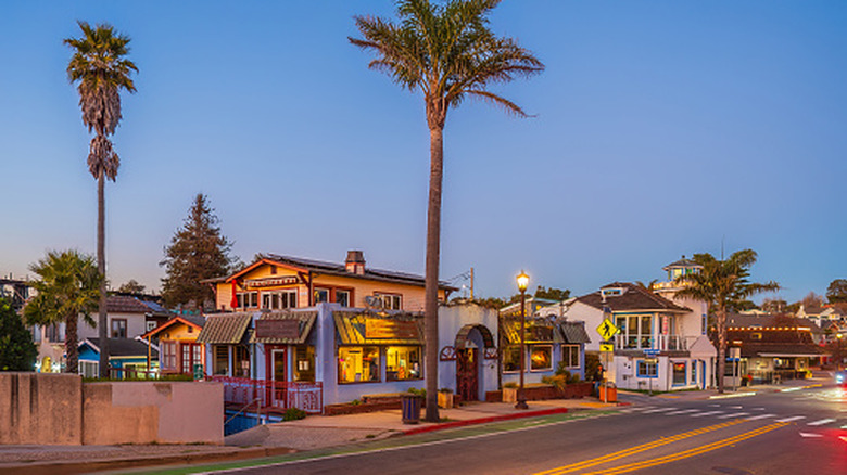 Evening street view of colorful storefronts and palm trees in Capitola, California.