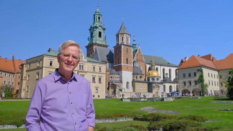 Rick Steves standing in front of historical buildings in Krakow