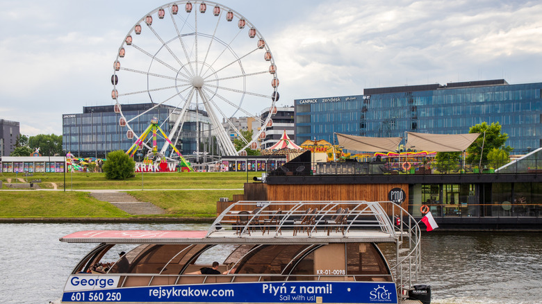 A cruise ship on the Vistula River in front of Kraków Eye with hotels and restaurants on the banks