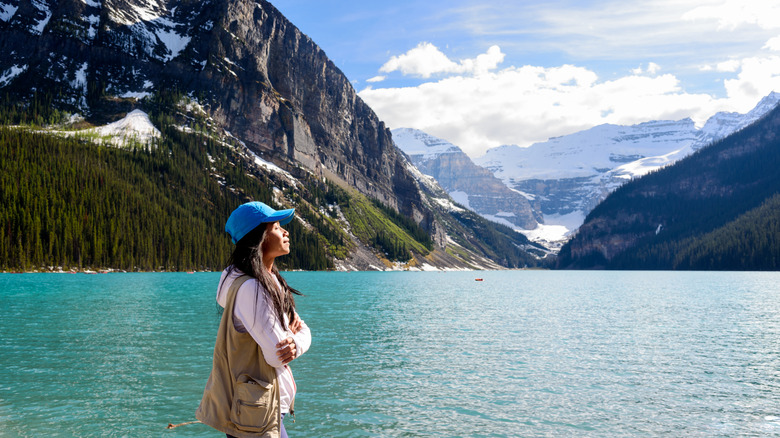 Serene looking woman in front of glacial lake and mountains in Canadian national park.