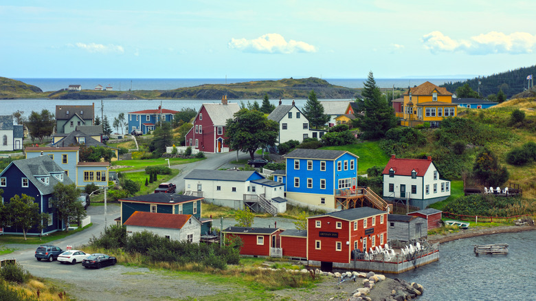 Colorful homes surrounded by green hills and water in a small town in Newfoundland.