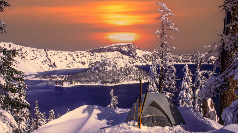 A tent is pictured in the snow with Crater Lake in the background.