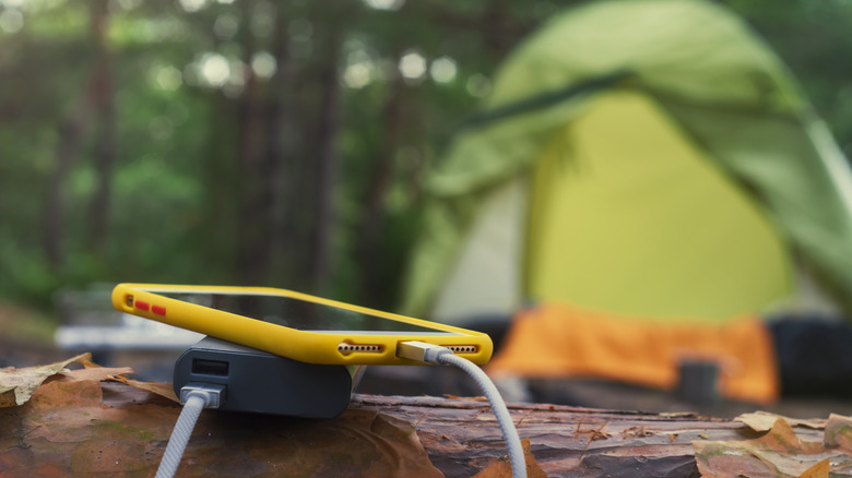 a cell phone charges with a phone bank with a tent in background