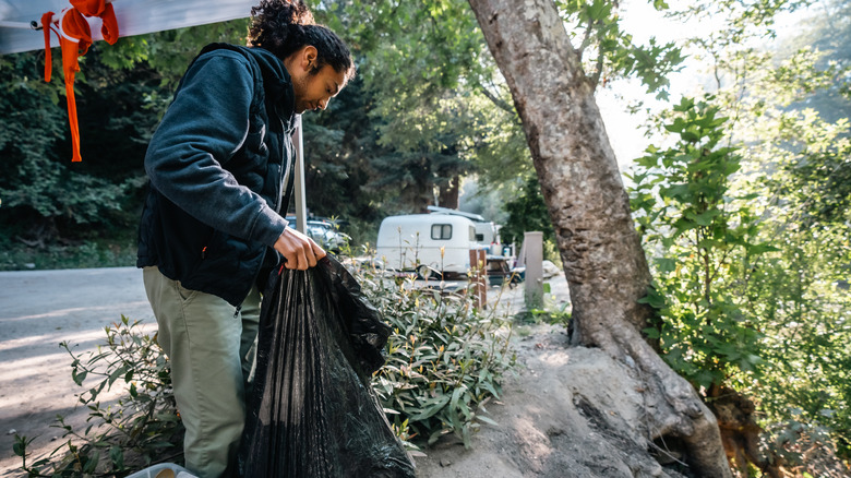 a camper holding a trash bag
