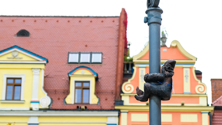 A statuette of a gnome climbing a light pole in the historic Market Square of Wrocław
