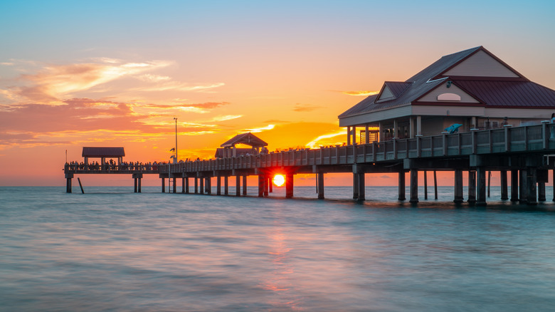 People gathered on Clearwater Beach Pier 60 to watch the sun set over the Gulf with a brilliant orange and pink sky in the background