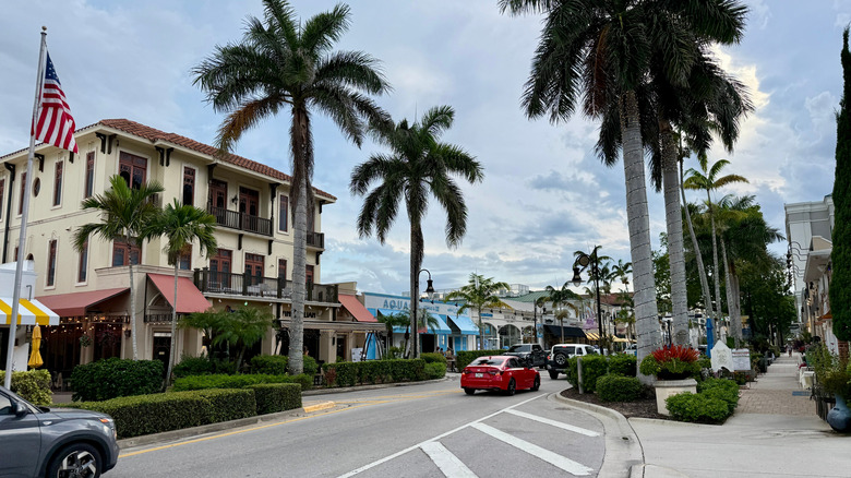 View of "Old Florida" style buildings and palm trees lining Fifth Avenue South in Naples, Florida on an overcast day