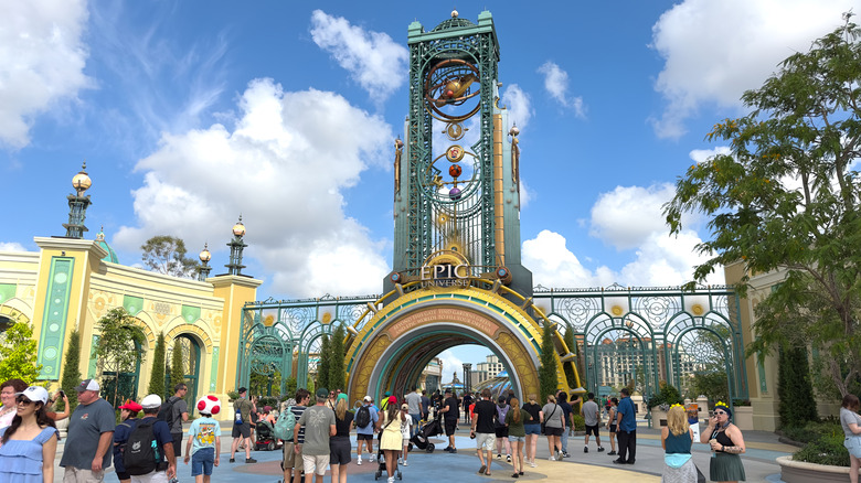 Guests entering the Art Nouveu-style entry "portal" at Universal Epic Universe theme park on a sunny day