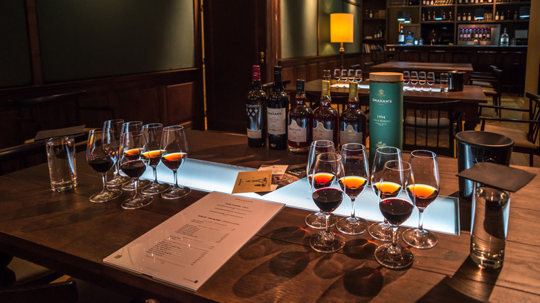Glasses filled with wine arranged on a wooden table with bottles and a menu