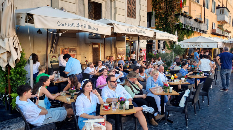 Tourists and locals enjoying an evening aperitivo at a restaurant in Rome, Italy