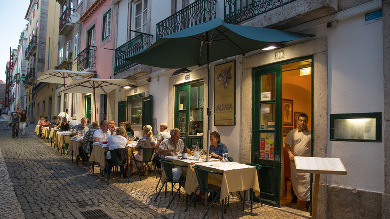 Diners sit at tables on a restaurant patio in Lisbon, Portugal.