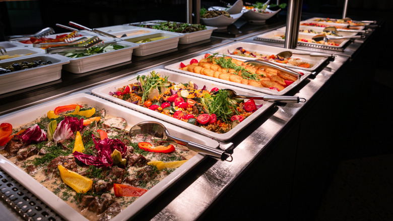 Buffet table holding trays filled with colorful food