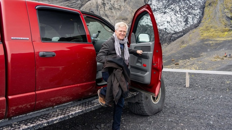 Rick Steves getting out of a red truck in a rugged setting