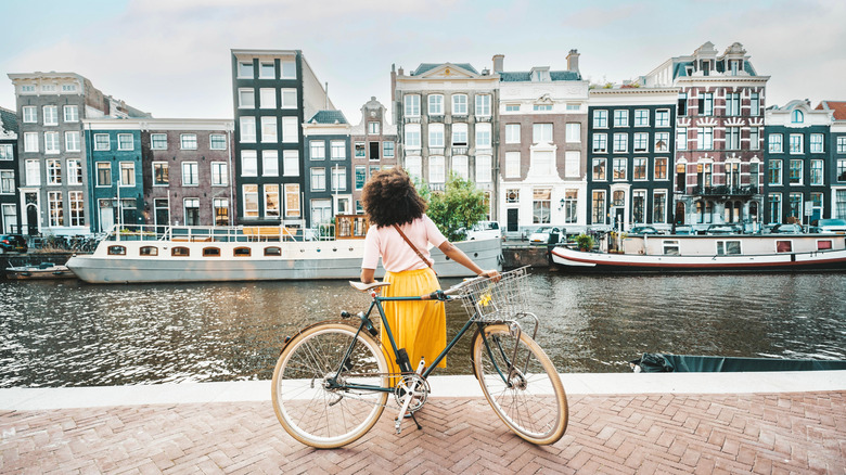 Woman in a skirt with a bicycle near an Amsterdam canal