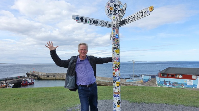 Rick Steves in Scotland, posing with the John o' Groats sign