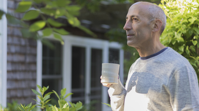A man enjoys coffee in a garden outside of a bed and breakfast
