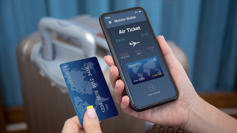 person holding phone and credit card while booking airplane ticket