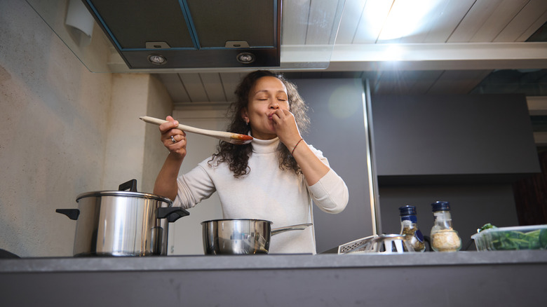 Chef's kiss gesture done by a woman cooking