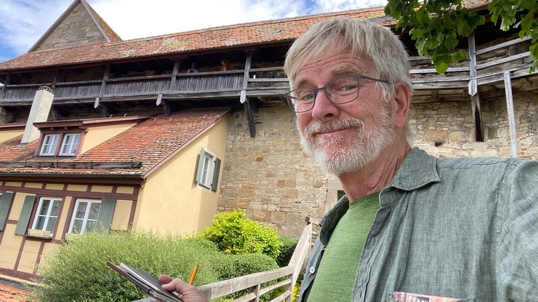 Rick Steves poses for a selfie in front of a historic home in Germany.