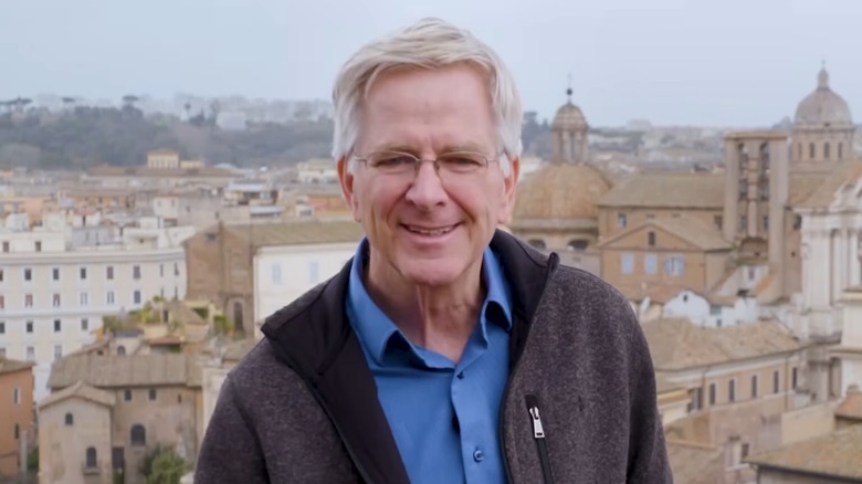 Rick Steves standing in front of a viewpoint in Rome, with buildings in the distance
