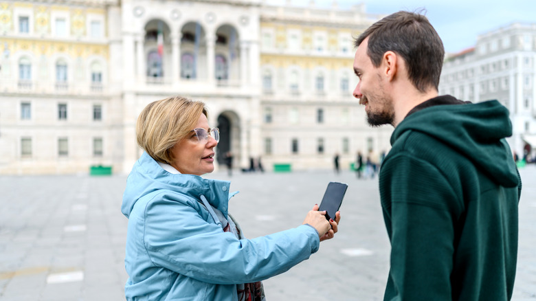 Tourist speaking to a local while pointing to their cellphone