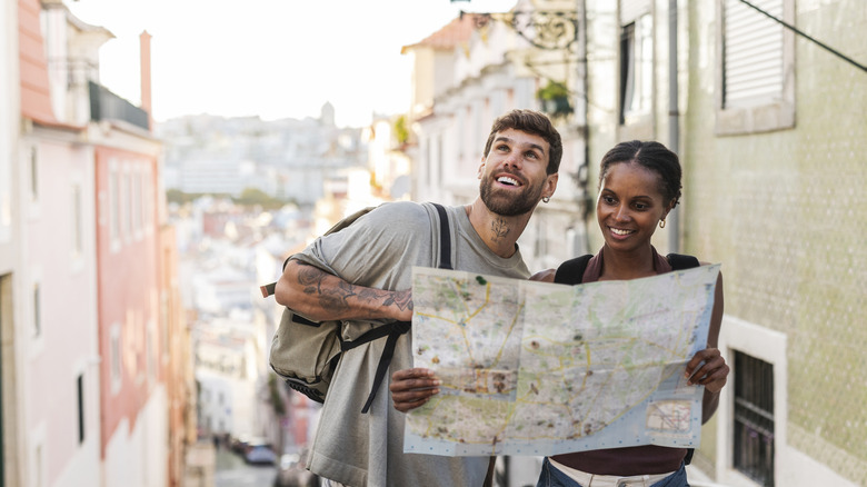 Two happy tourists consulting a map while exploring a city