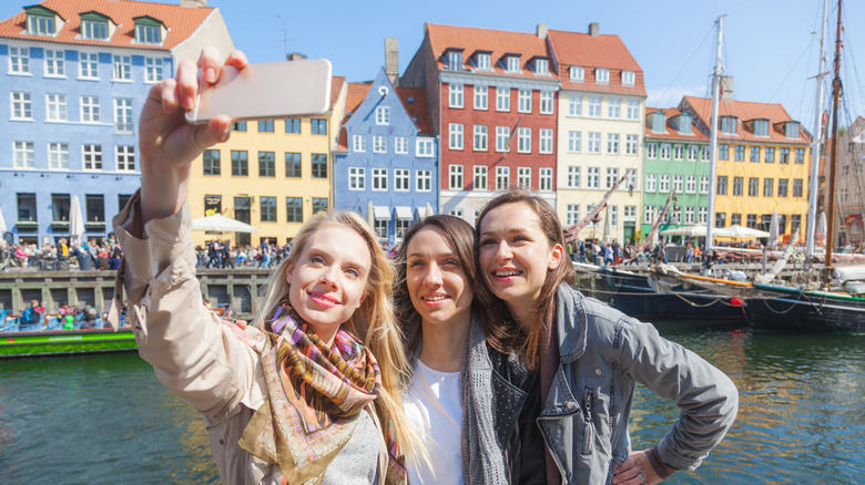 Group of women taking a selfie in Copenhagen with colorful houses on background .